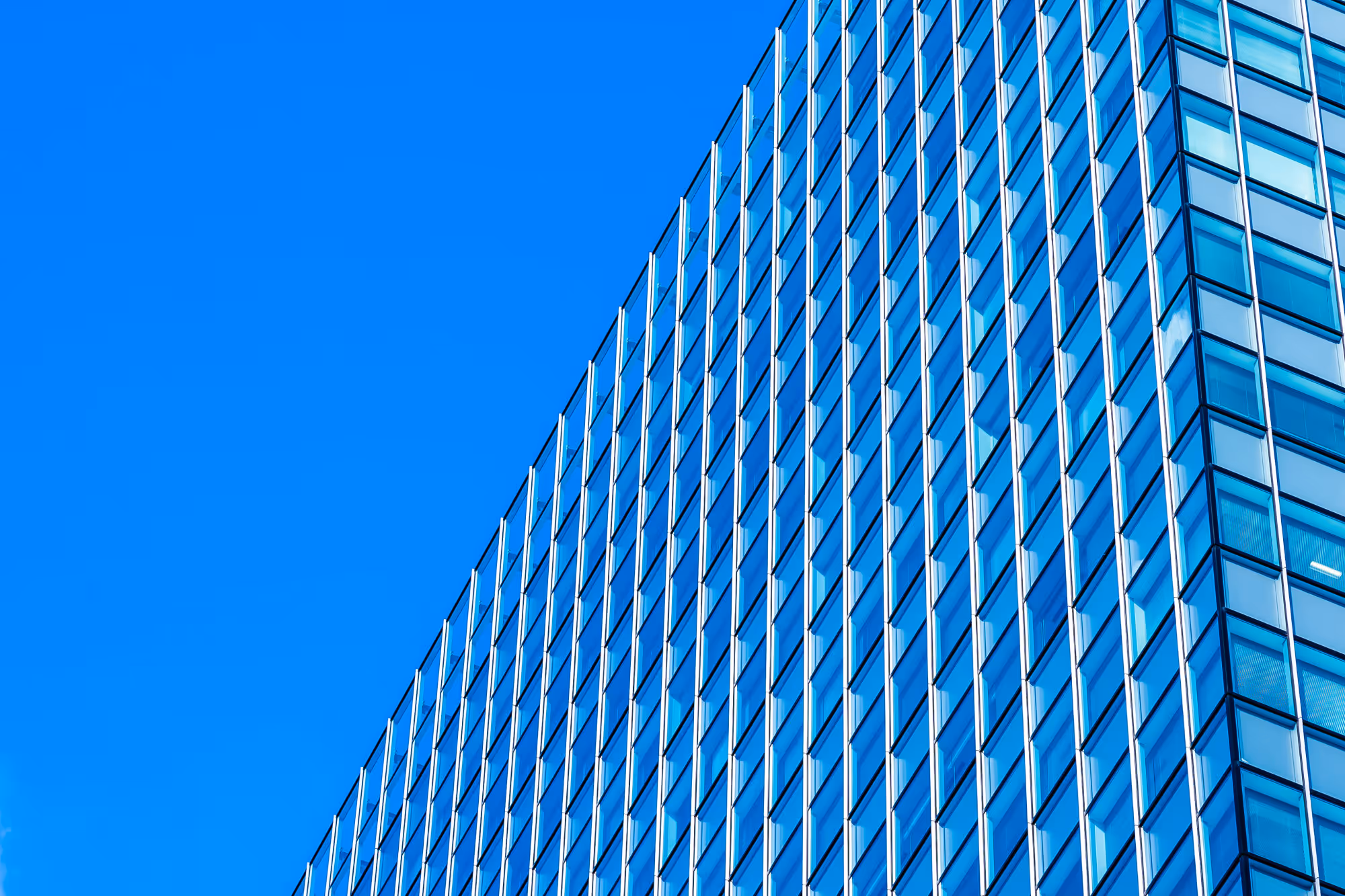 Construction worker wearing a blue helmet climbing a steel frame structure under a cloudy sky.